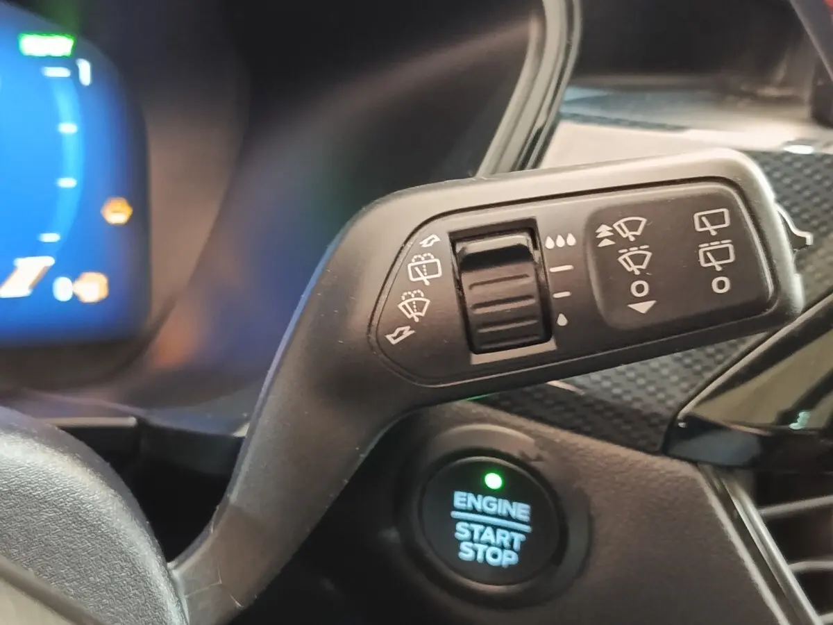Gros plan sur la commande d’essuie-glace et le bouton start/stop du tableau de bord intérieur du Ford Kuga gris foncé.