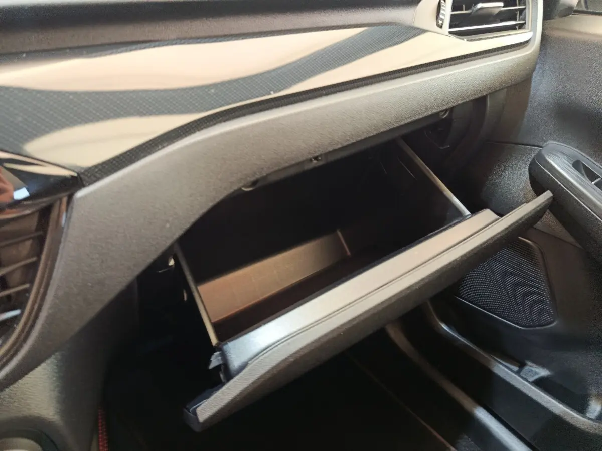 Gros plan sur la boîte à gants ouverte côté passager du Ford Kuga 2.5 Hybrid ST-Line X 2023, intérieur noir.