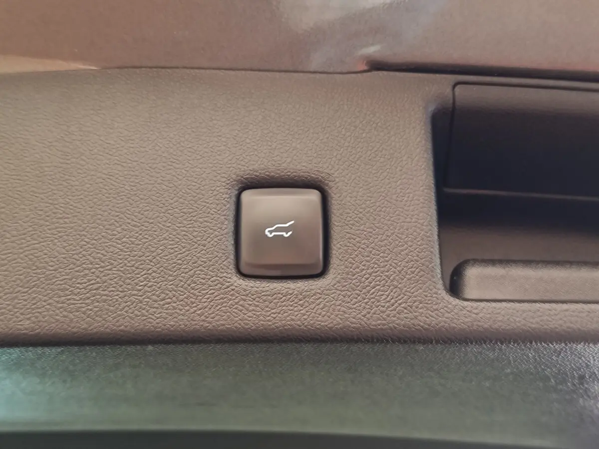 Bouton d'ouverture électrique du coffre sur le panneau intérieur d'un Ford Kuga gris foncé, vue rapprochée.