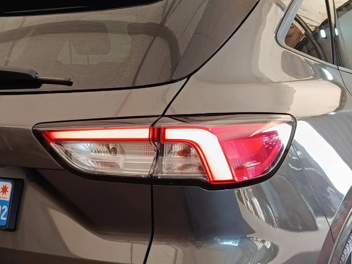 Feu arrière droit allumé d’un Ford Kuga gris foncé, vue rapprochée du coin arrière du véhicule.