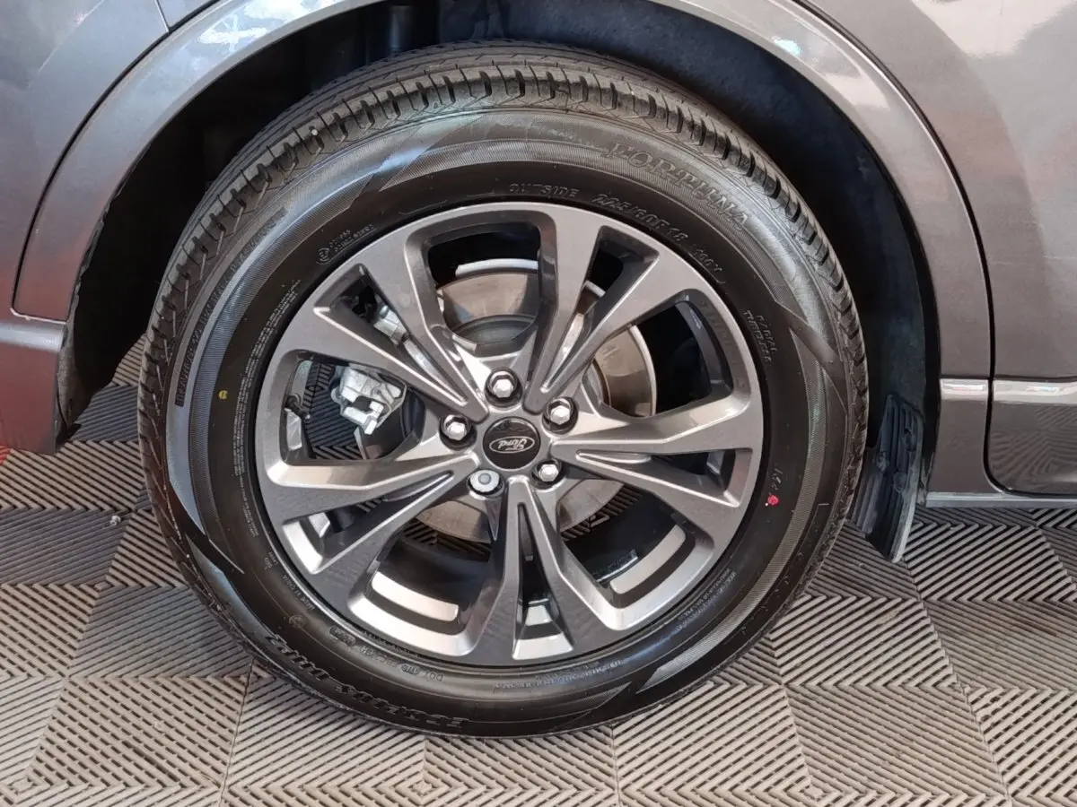 Gros plan sur la roue avant droite gris foncé du Ford Kuga 2023 avec jante alliage et logo Ford au centre.