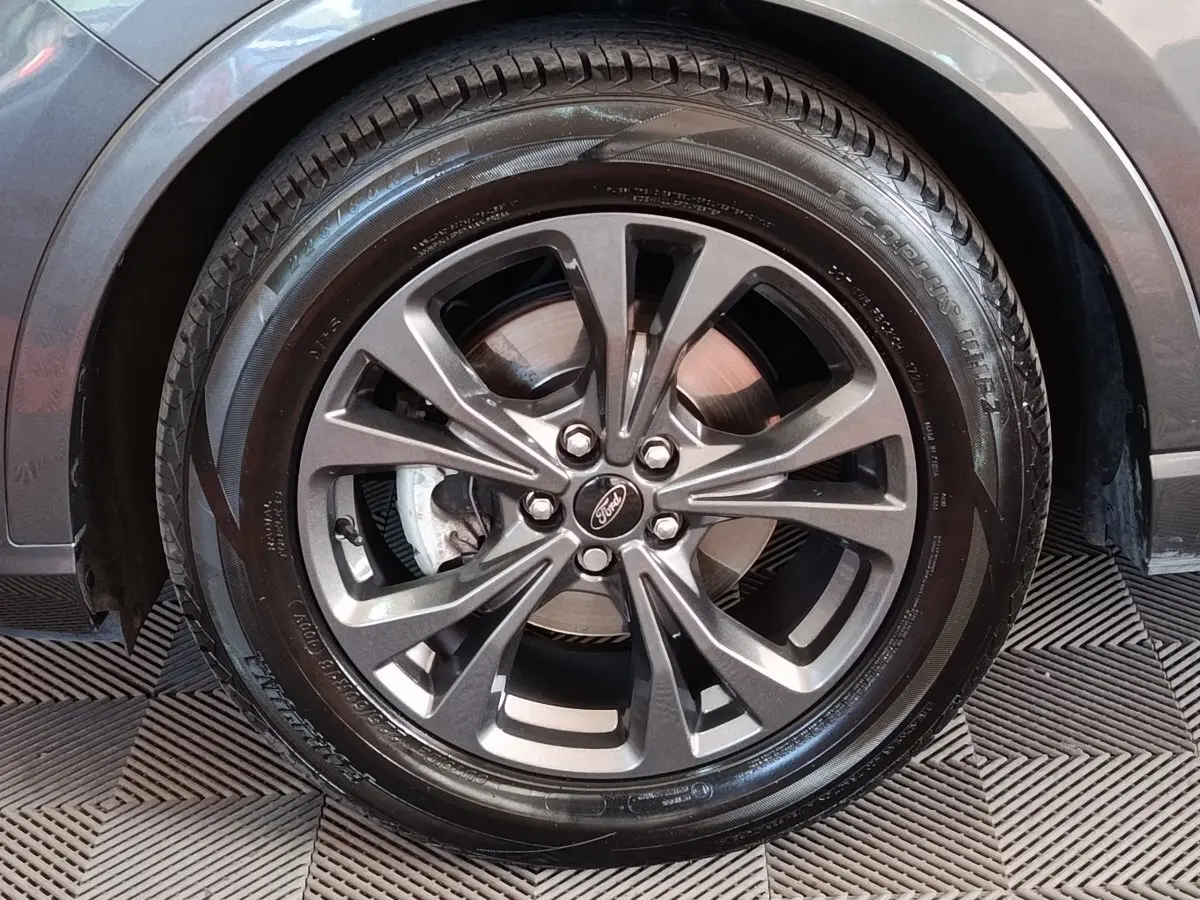Gros plan sur la roue avant droite gris foncé du Ford Kuga 2023 avec jante alliage et logo Ford au centre.