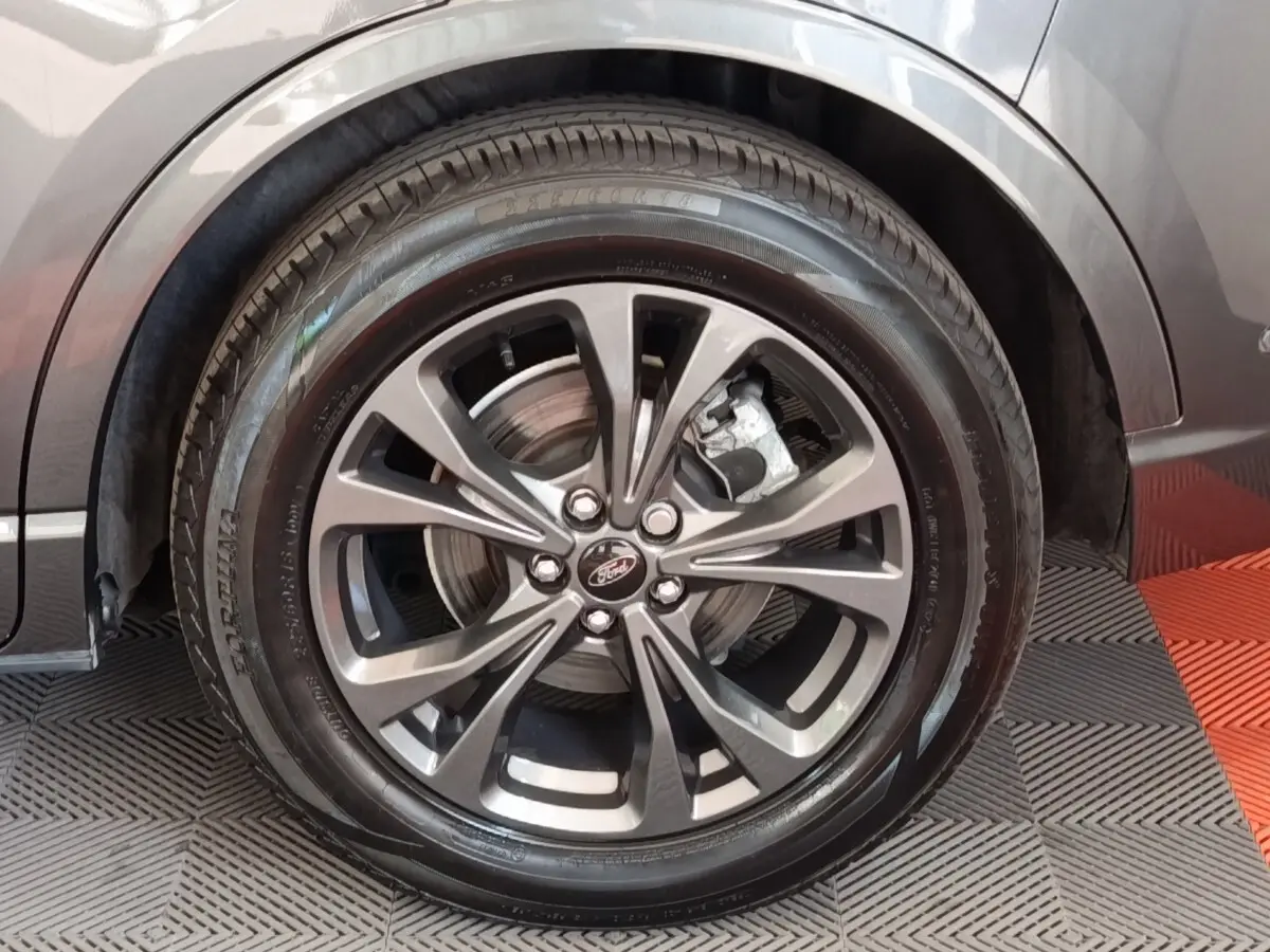 Gros plan sur la roue avant droite gris foncé du Ford Kuga 2023 avec jante alliage et logo Ford au centre.