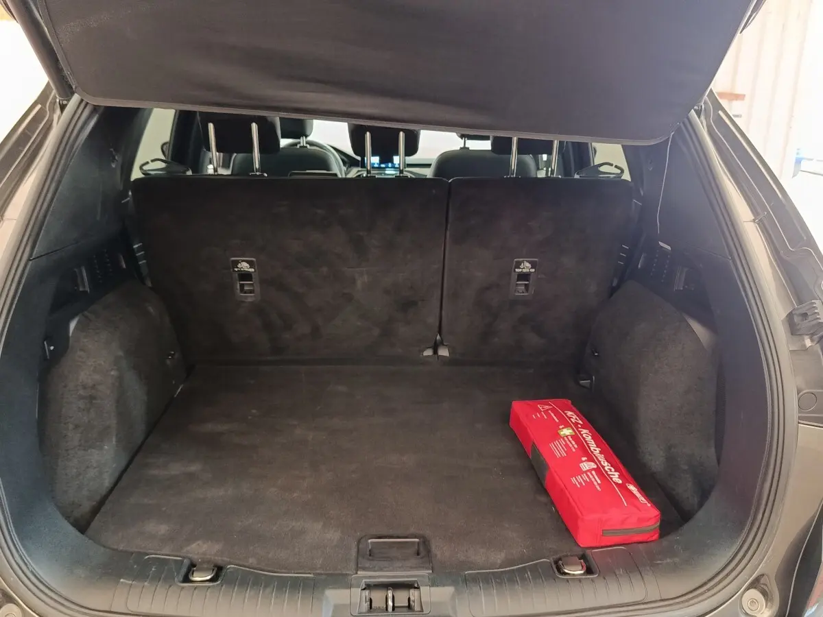 Coffre ouvert du Ford Kuga gris foncé vu de l'arrière, avec banquette arrière relevée et trousse de secours rouge.