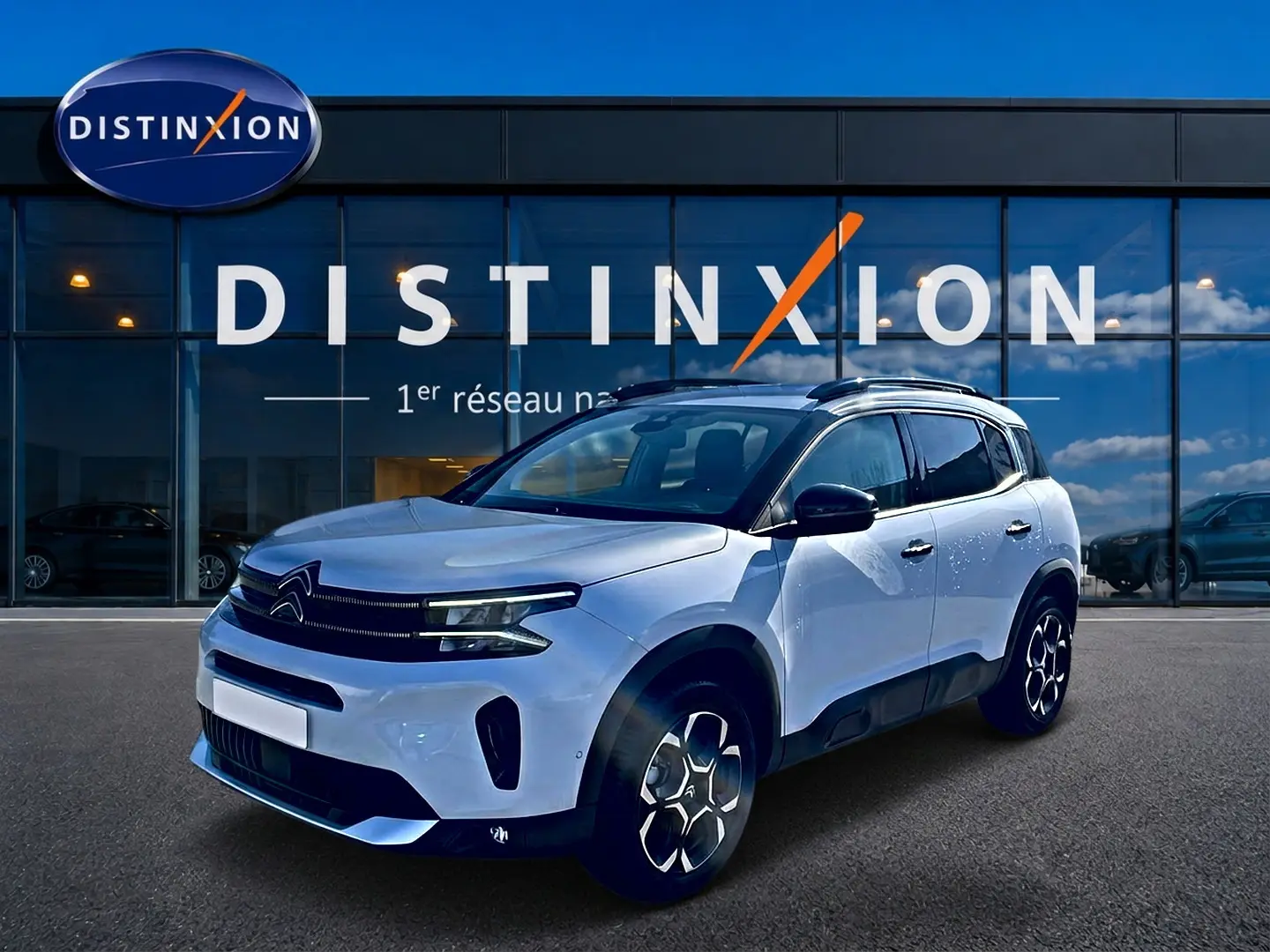 Citroën C5 Aircross blanc vue 3/4 avant droit, avec barres de toit et jantes alu distinctives.