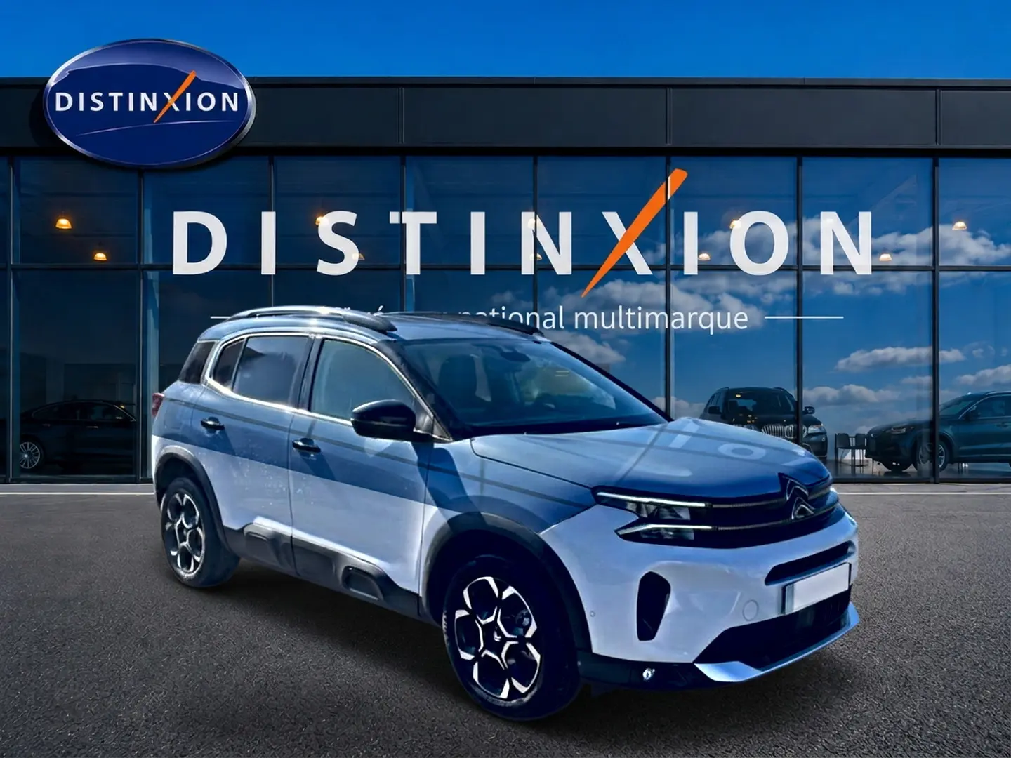 Citroën C5 Aircross blanc vue 3/4 avant droit, avec barres de toit et jantes alu distinctives.