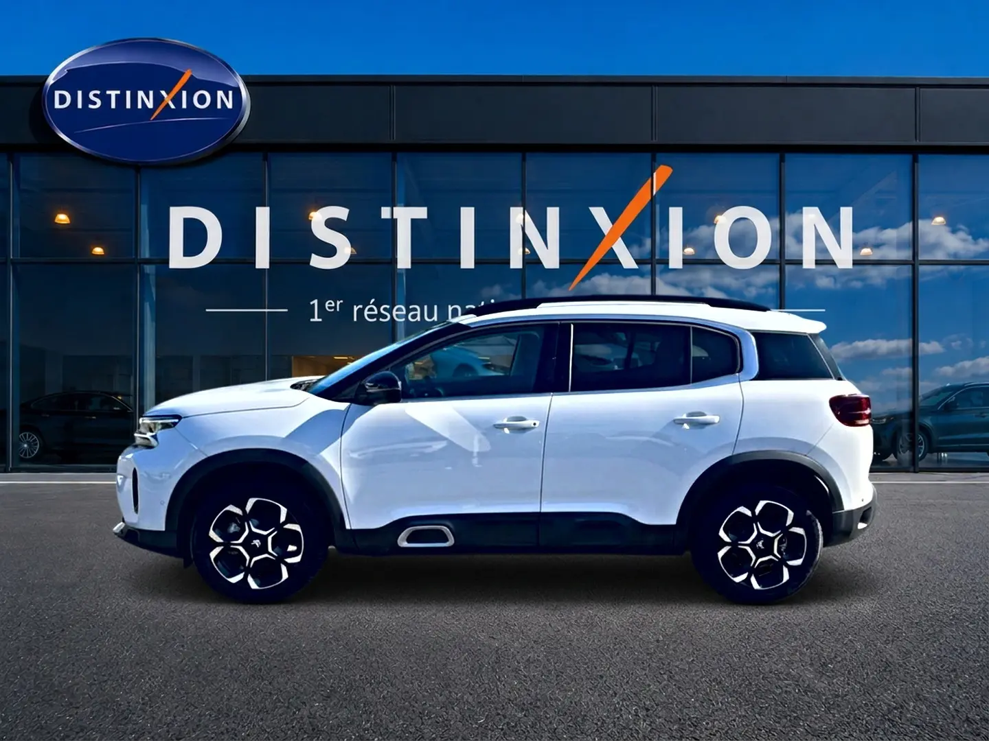 Profil droit d'un Citroën C5 Aircross blanc 2025 avec jantes alu distinctives et barres de toit noires.