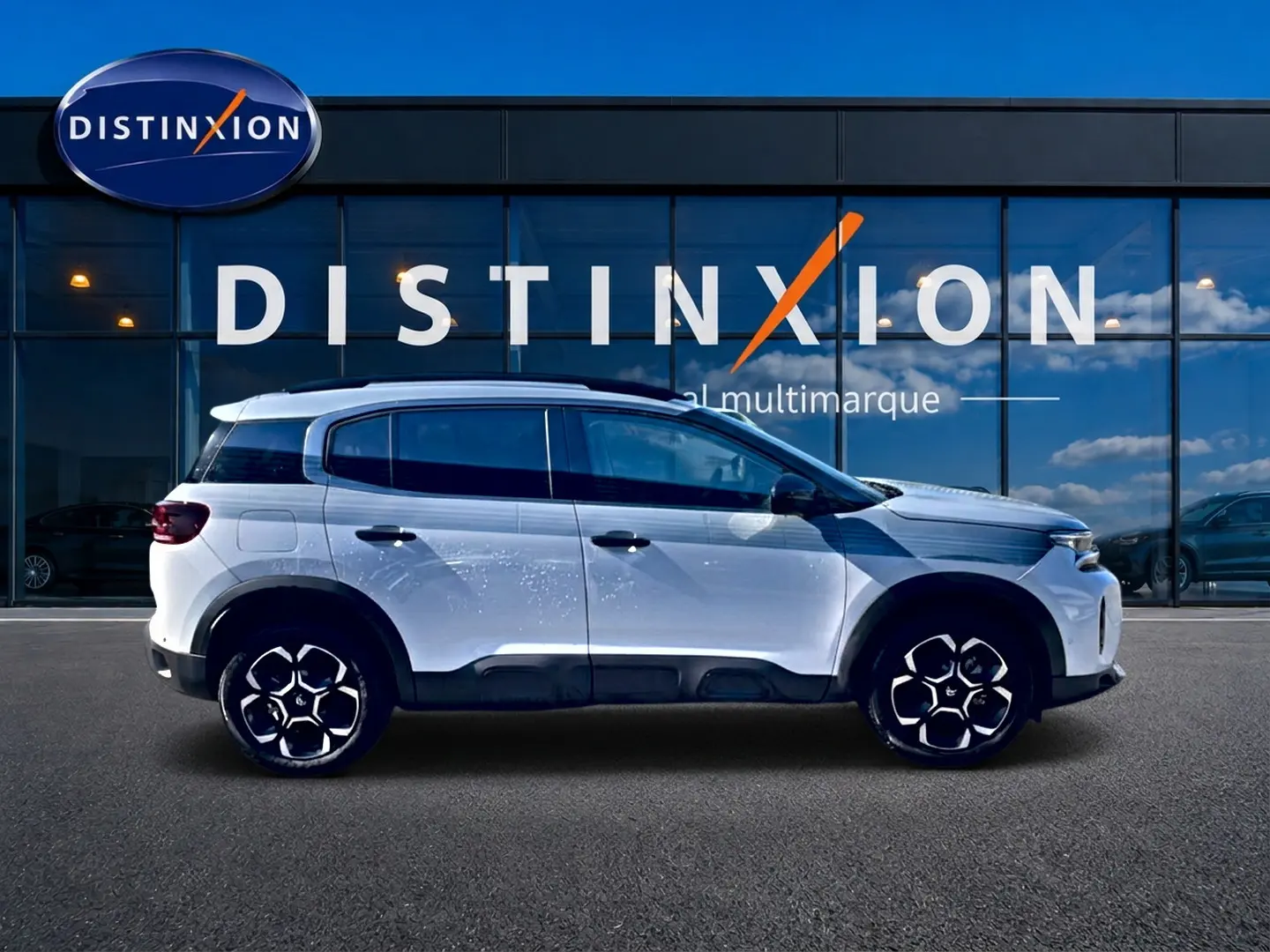 Profil droit du Citroën C5 Aircross blanc 2025 avec jantes alu et barres de toit devant vitrine Distinxion.