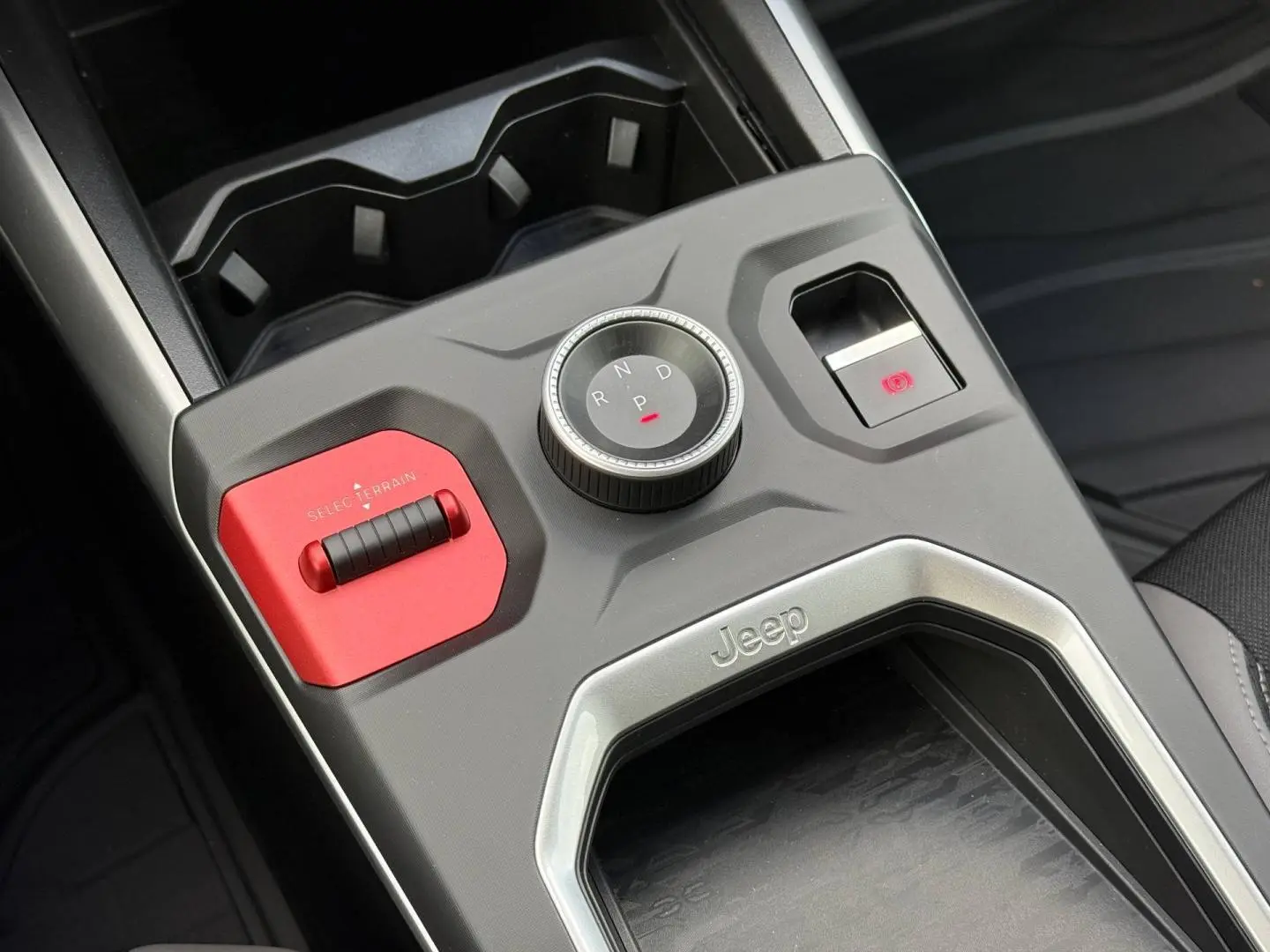 Vue rapprochée de la console centrale du Jeep Compass 2026, avec molette de boîte auto et bouton rouge Select Terrain.
