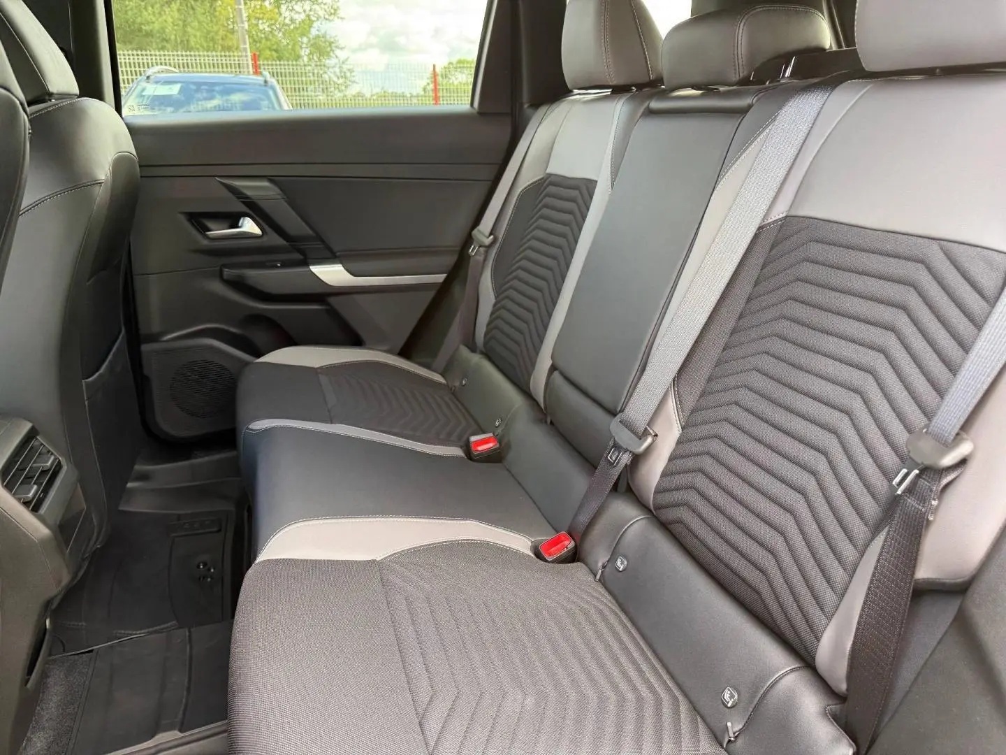 Vue latérale intérieure des sièges arrière gris et noirs du Jeep Compass 2026 avec ceintures de sécurité visibles.