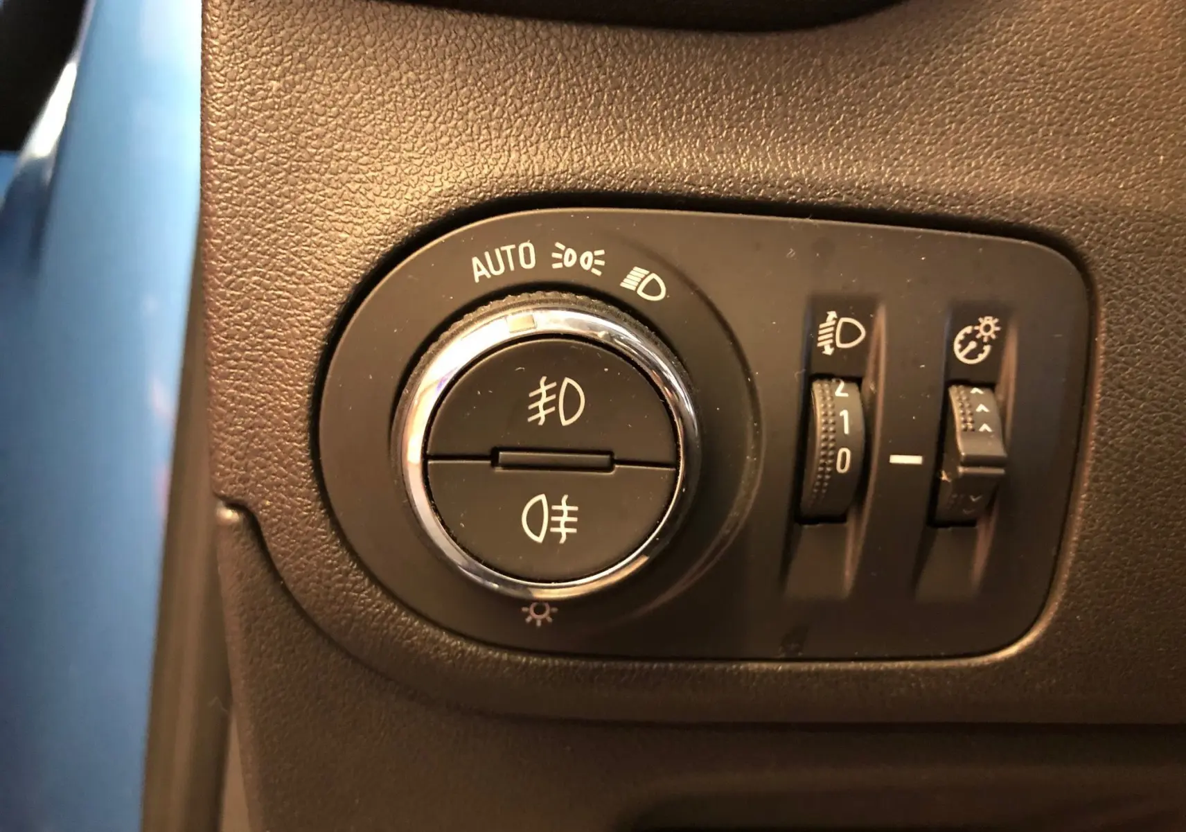 Gros plan sur les commandes d'éclairage du tableau de bord d'une Opel Crossland X bleu intens metal.