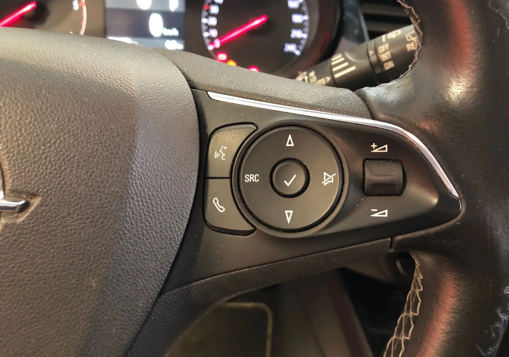 Gros plan sur les commandes du volant côté gauche d'un Opel Crossland X 2019 au cuir noir avec boutons multifonctions.