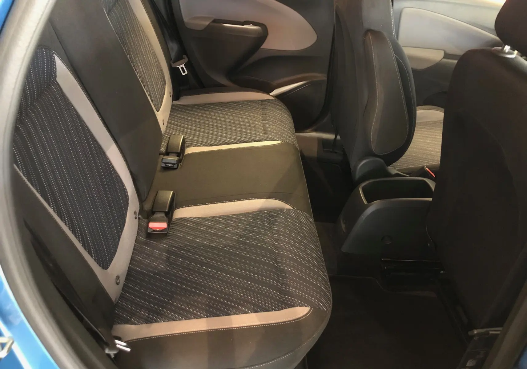 Vue intérieure côté arrière gauche de l'Opel Crossland X bleu intens métal, sièges tissu noir avec surpiqûres grises.
