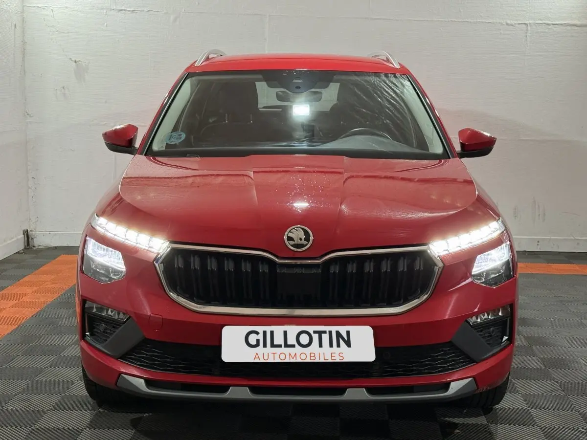 Vue frontale d'un Skoda Kamiq rouge 2024 avec phares LED allumés et calandre noire distinctive.