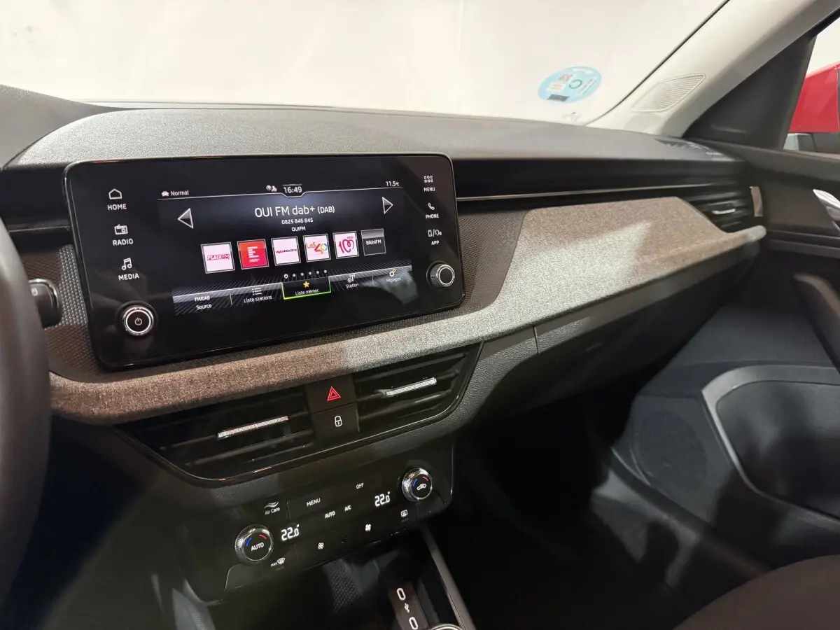 Intérieur du Skoda Kamiq 2024, vue du tableau de bord avec écran tactile central et finition tissu gris clair.