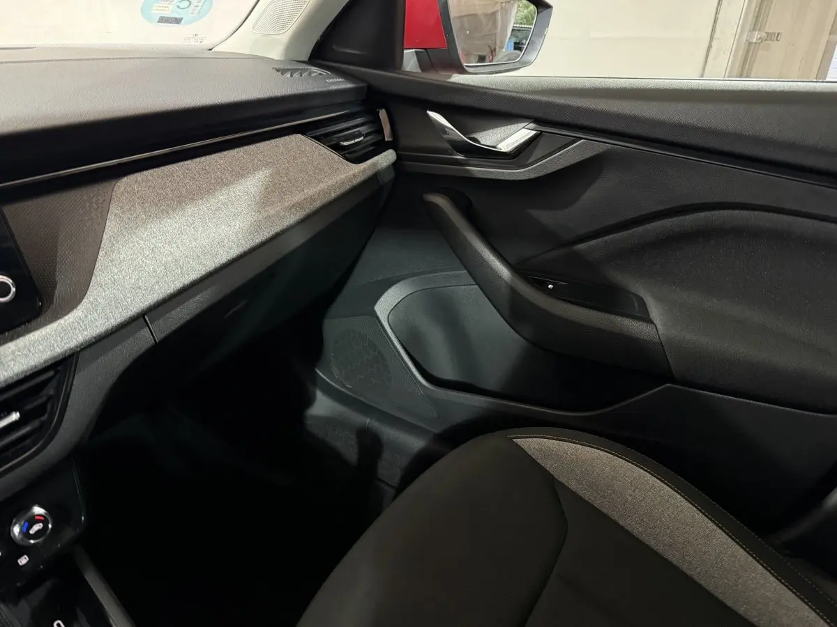 Intérieur côté passager du Skoda Kamiq 2024, tableau de bord et portière noirs avec insert gris clair.