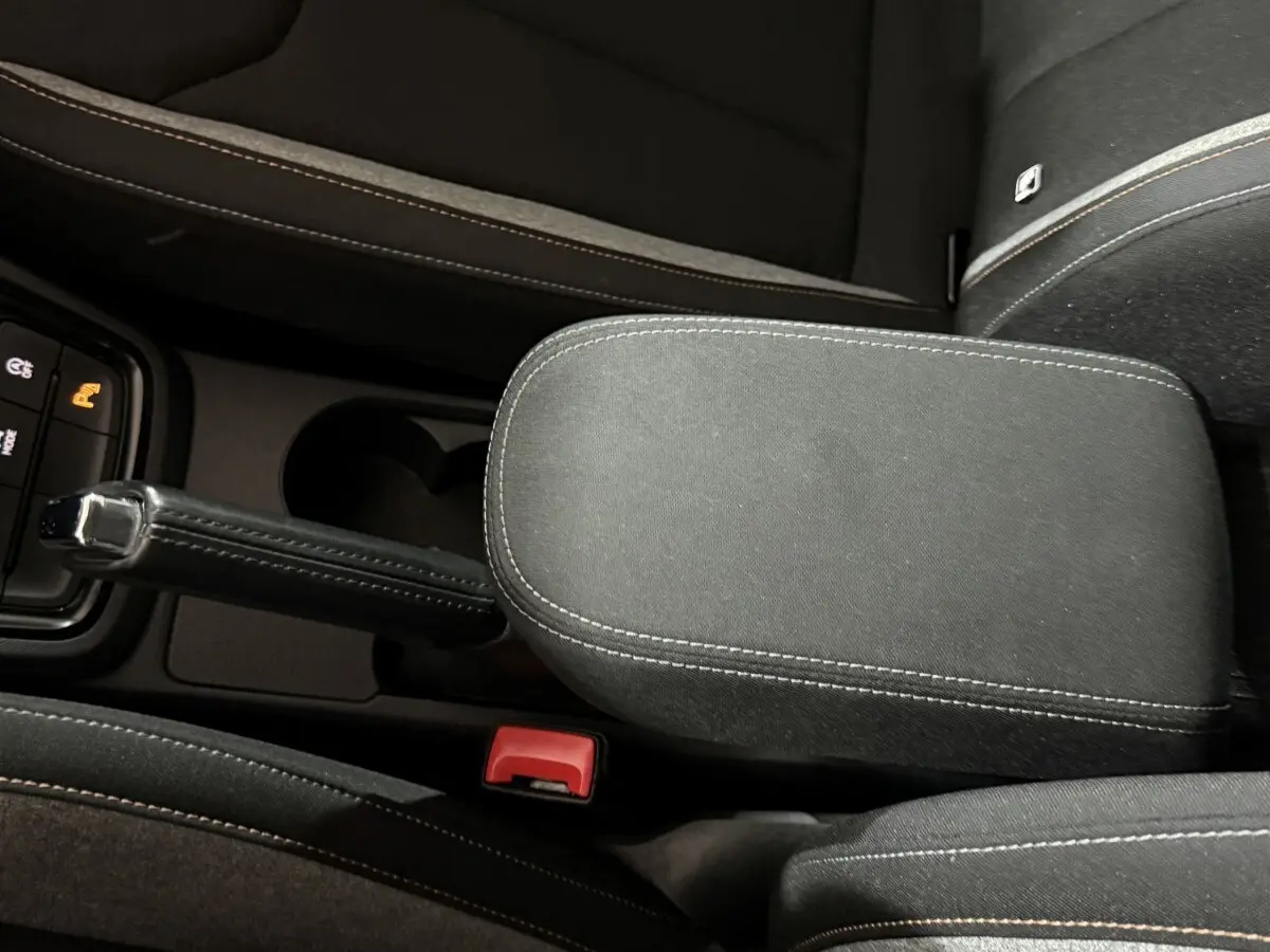 Vue rapprochée de la console centrale noire avec frein à main manuel et accoudoir du Skoda Kamiq 2024.