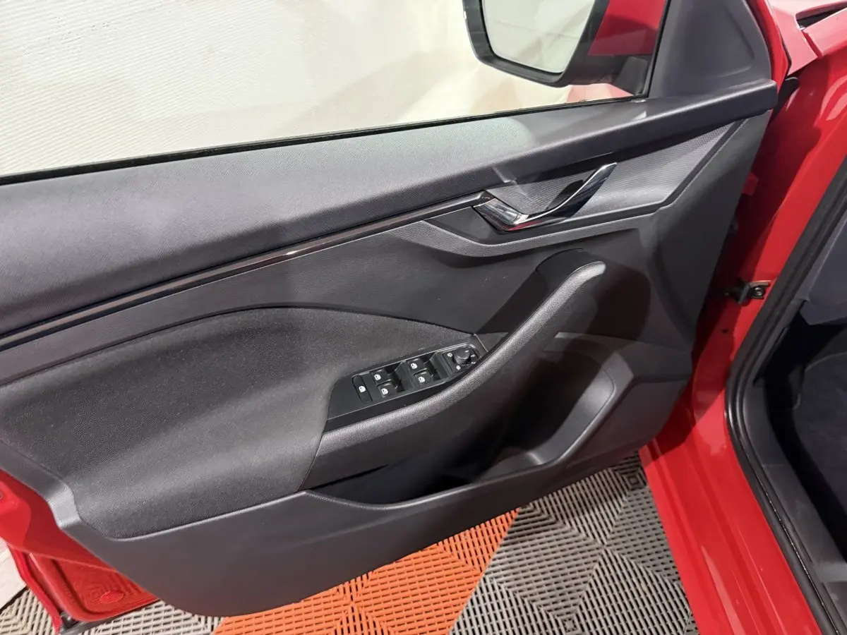 Gros plan sur la porte avant gauche rouge du Skoda Kamiq 2024, avec commandes électriques des vitres et poignée intégrée.