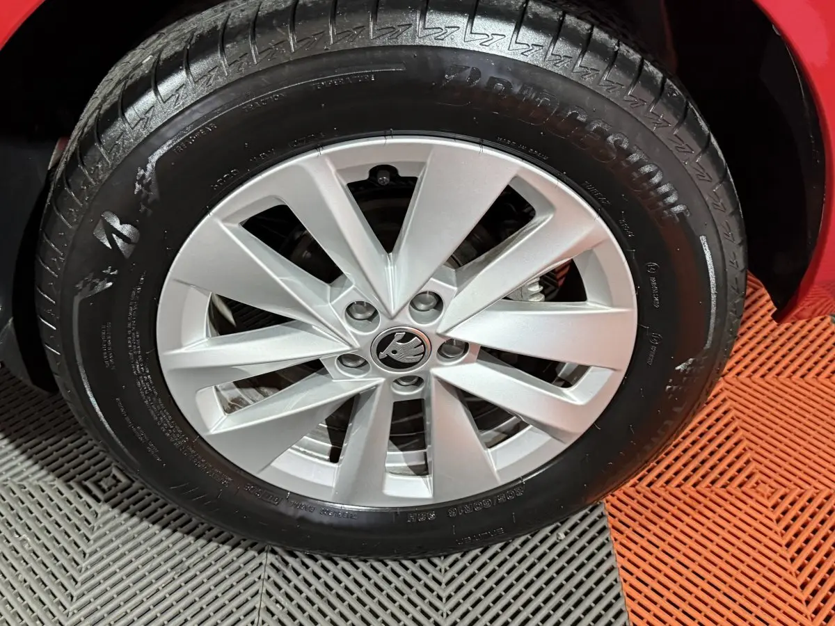 Gros plan sur la roue avant droite d’un Skoda Kamiq rouge, mettant en valeur la jante argentée au design moderne.