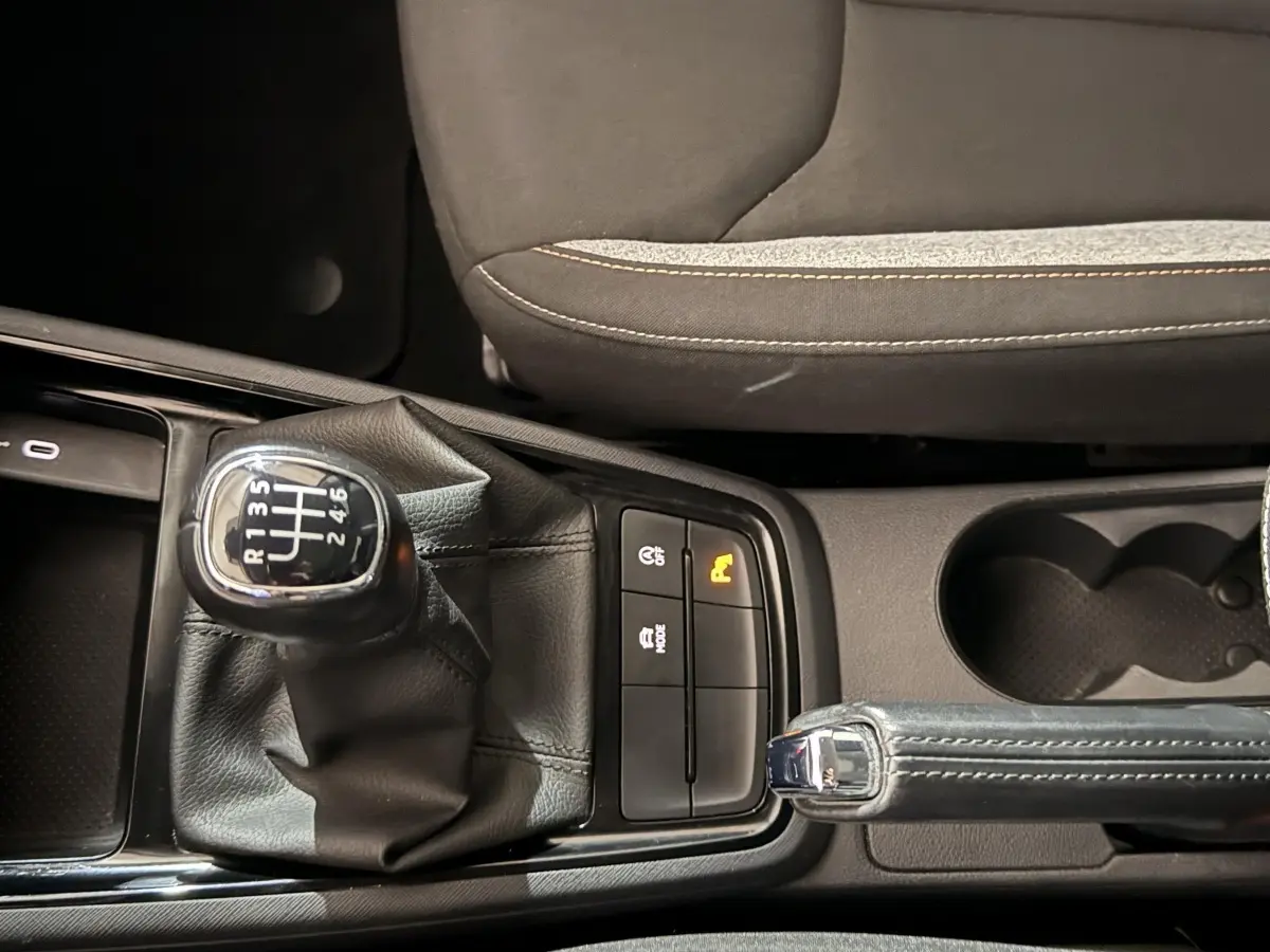 Gros plan sur la commande de boîte manuelle et frein à main cuir dans l’habitacle du Skoda Kamiq rouge 2024.