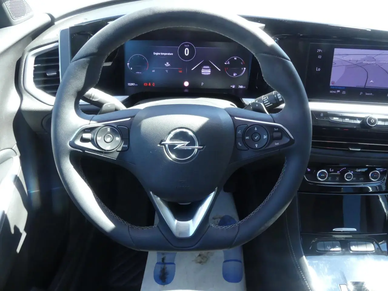 Vue intérieure centrée sur le volant noir de l'Opel Grandland 2024 avec tableau de bord numérique et écran tactile.