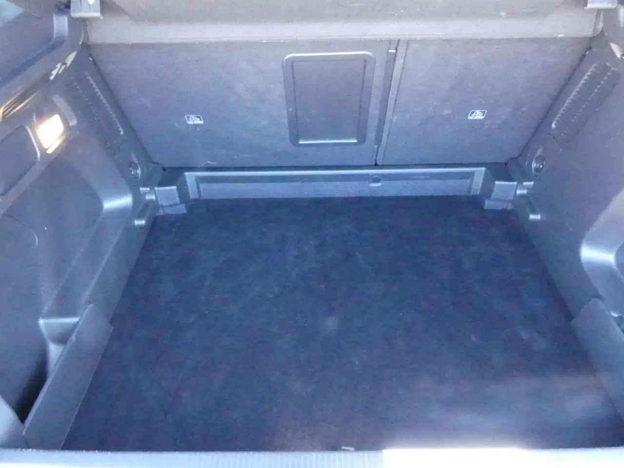 Coffre vide vu de face de l’Opel Grandland blanc métallisé avec intérieur noir et éclairage latéral.