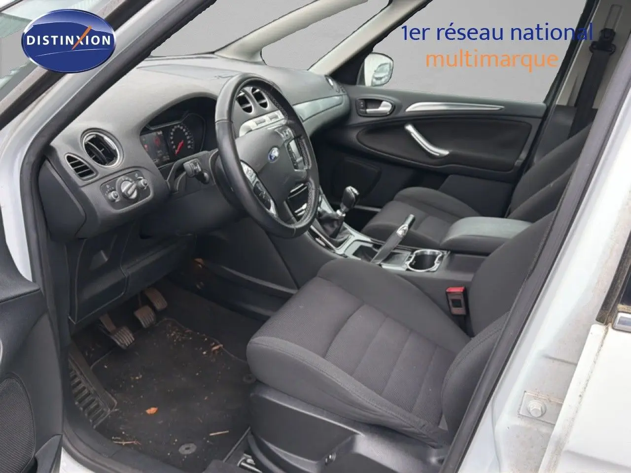 Intérieur avant droit du Ford S-MAX blanc 2013, montrant les sièges noirs, le volant et la boîte manuelle.