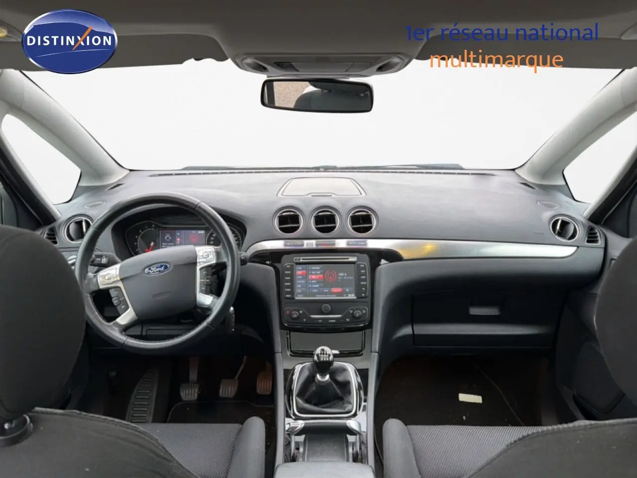 Vue intérieure avant du Ford S-MAX 2013 avec tableau de bord noir, volant multifonction et boîte manuelle.