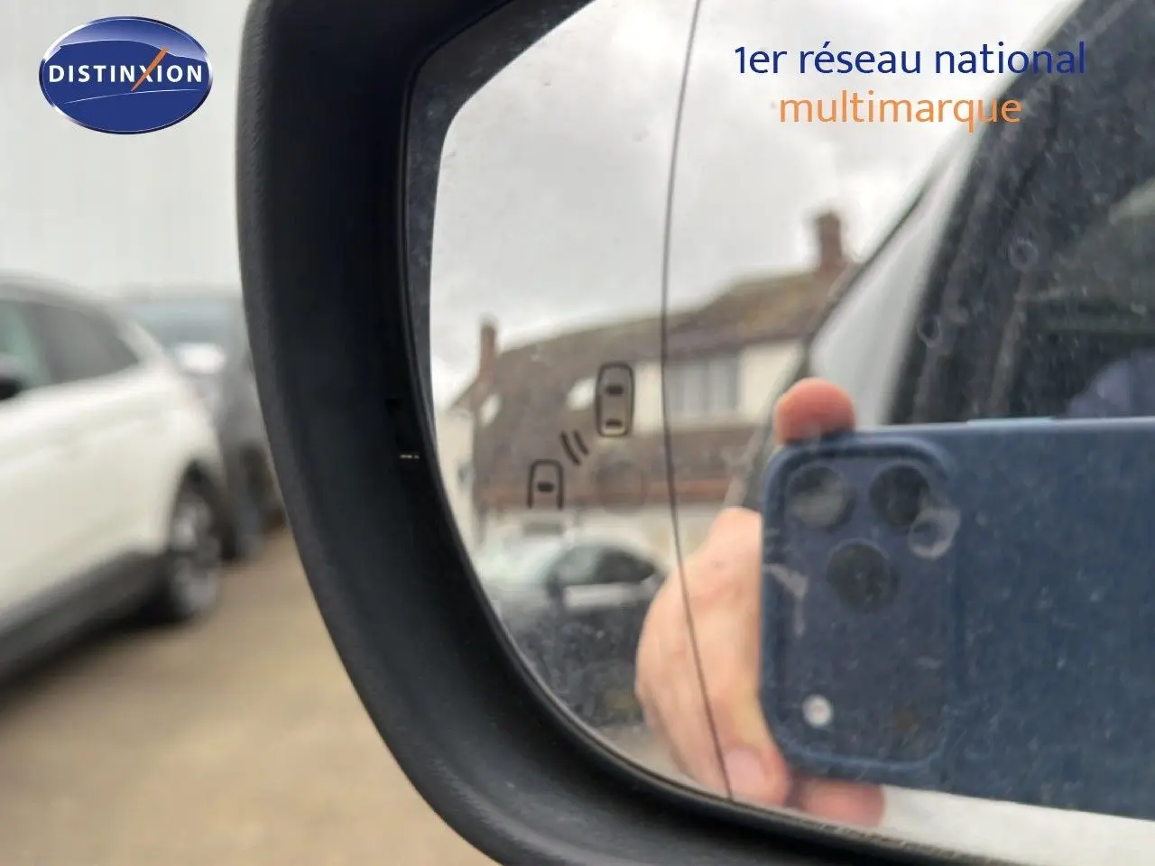 Rétroviseur extérieur gauche d’un Ford S-MAX blanc de 2013, avec reflet flou d’un bâtiment et d’un téléphone.