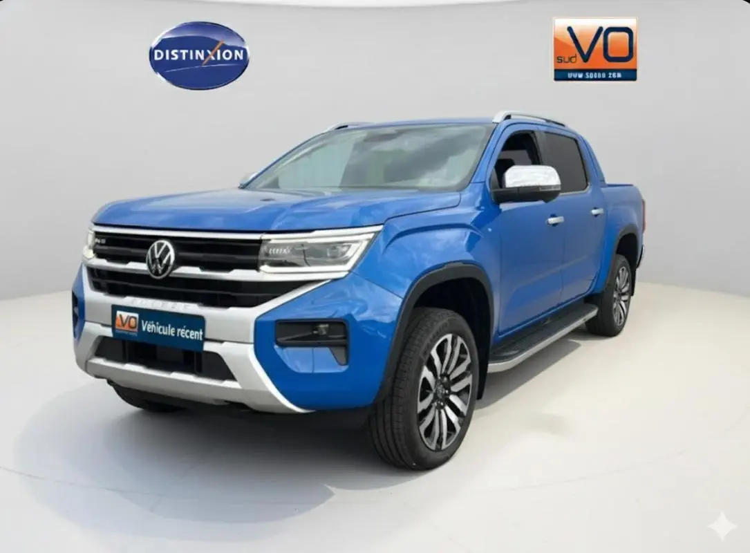 Vue 3/4 avant droite du Volkswagen Amarok bleu avec jantes alliage 21 pouces et marchepieds visibles.