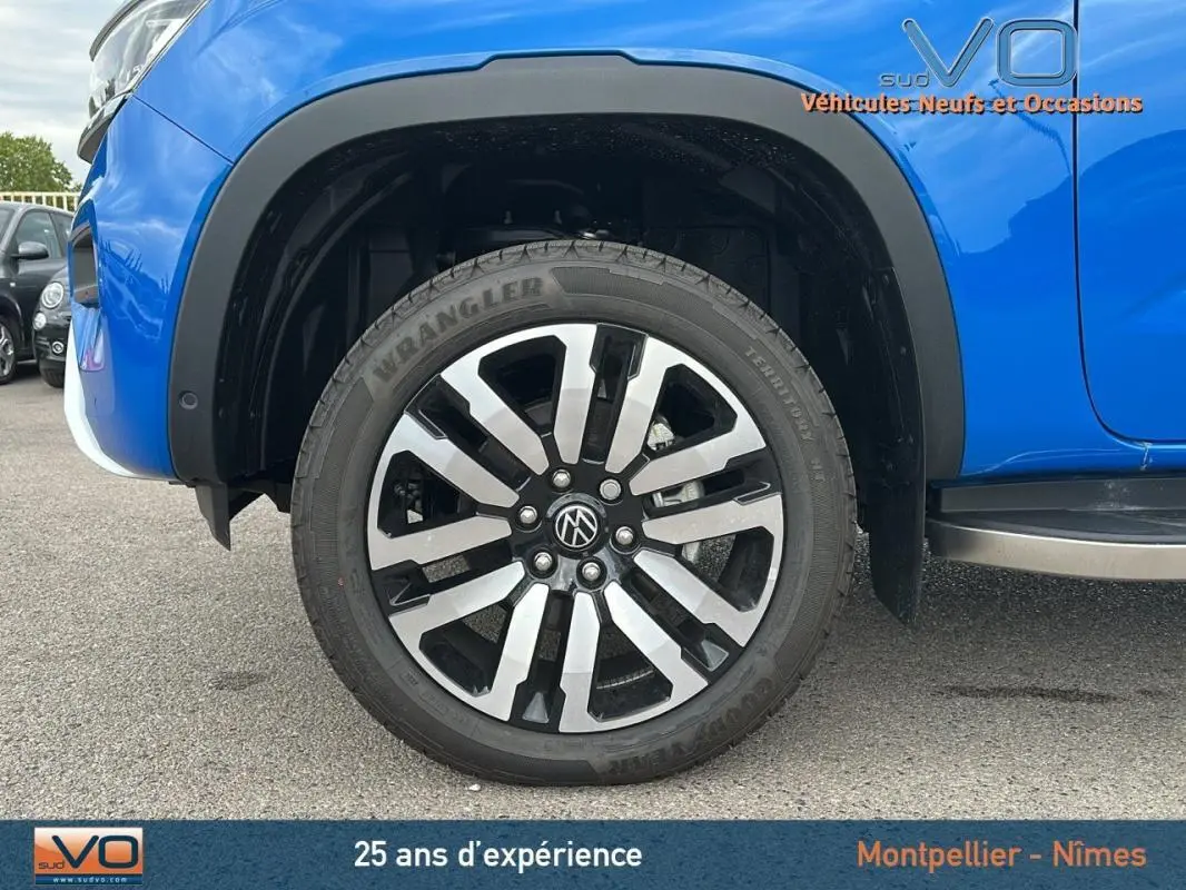 Gros plan sur la roue avant droite du Volkswagen Amarok bleu 2025 avec jante alliage 21 pouces et marchepied visible.