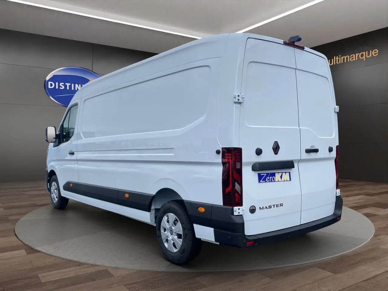 Vue 3/4 arrière droite d’un Renault Master blanc avec portes arrière tôlées et enjoliveurs noirs au sol en showroom.