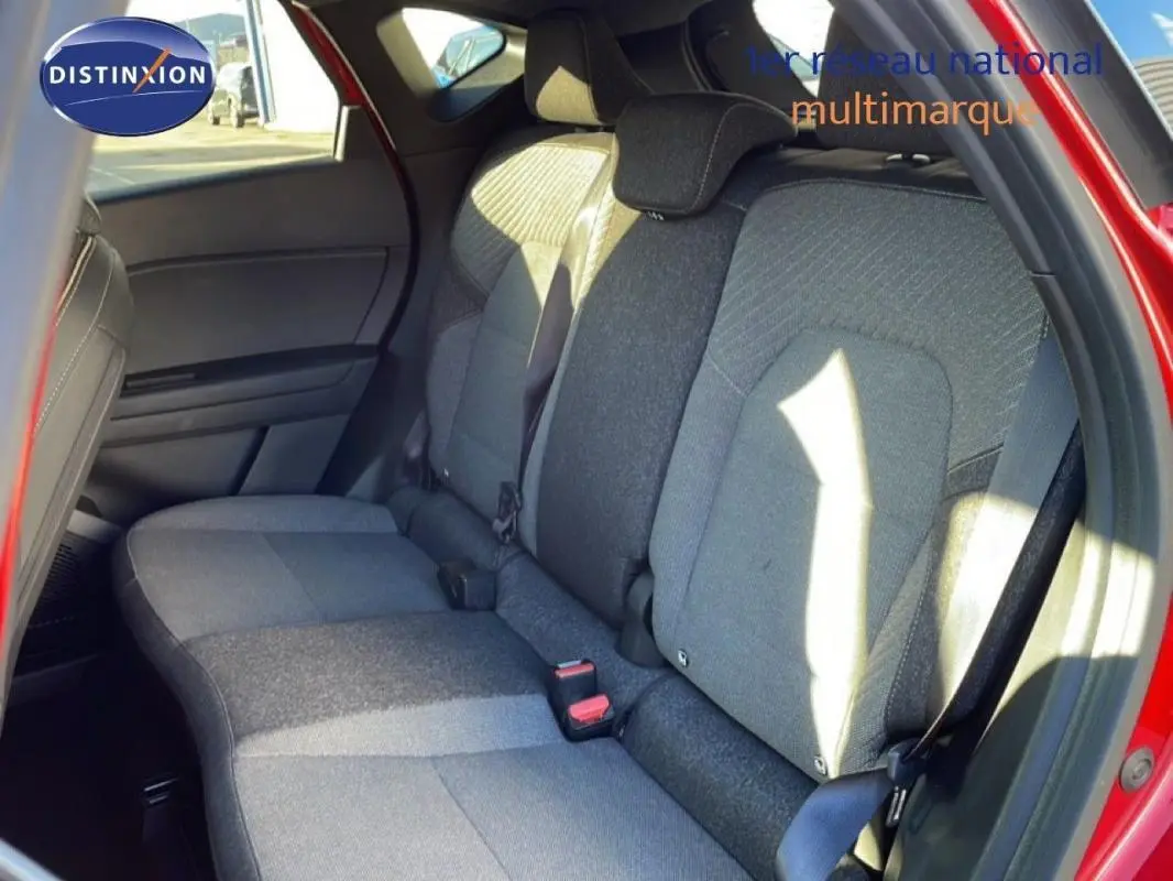 Vue intérieure sur les sièges arrière gris du Renault Captur rouge, avec ceinture de sécurité et porte arrière ouverte.