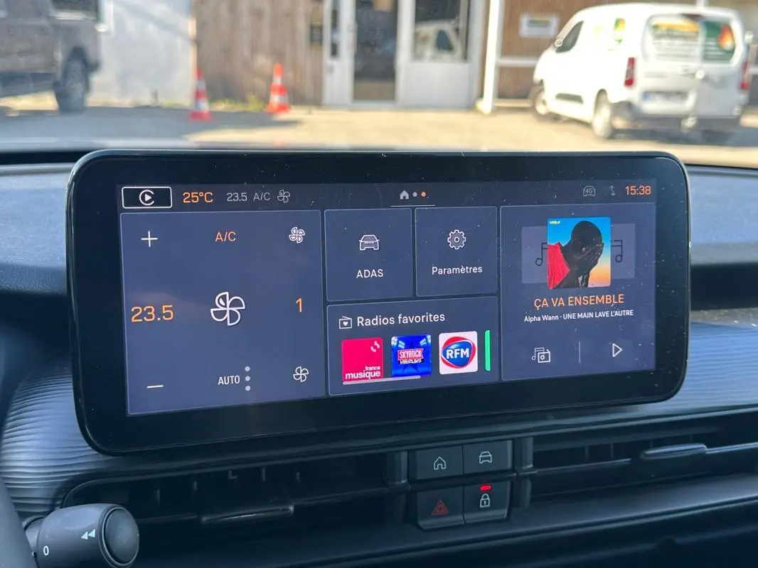 Écran tactile central affichant la climatisation et les radios favorites dans un Jeep Avenger gris, vue intérieure frontale.