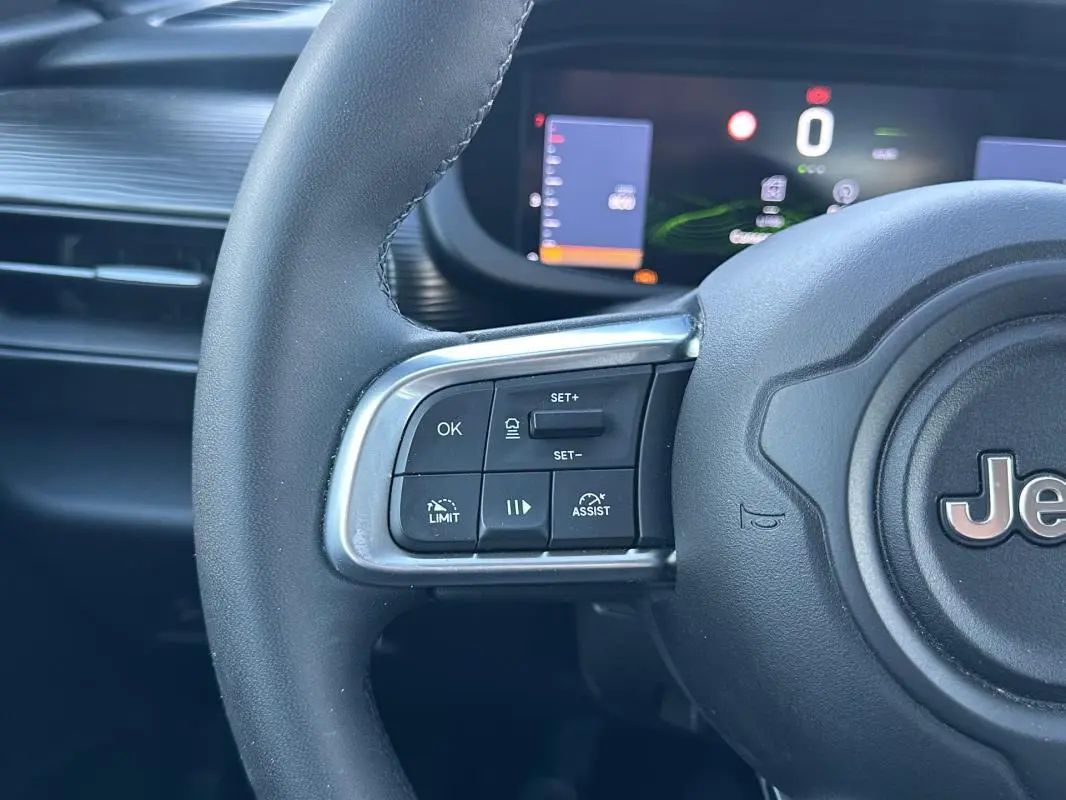 Gros plan sur le volant noir de la Jeep Avenger 2025 avec commandes de régulateur et tableau de bord numérique en arrière-plan.