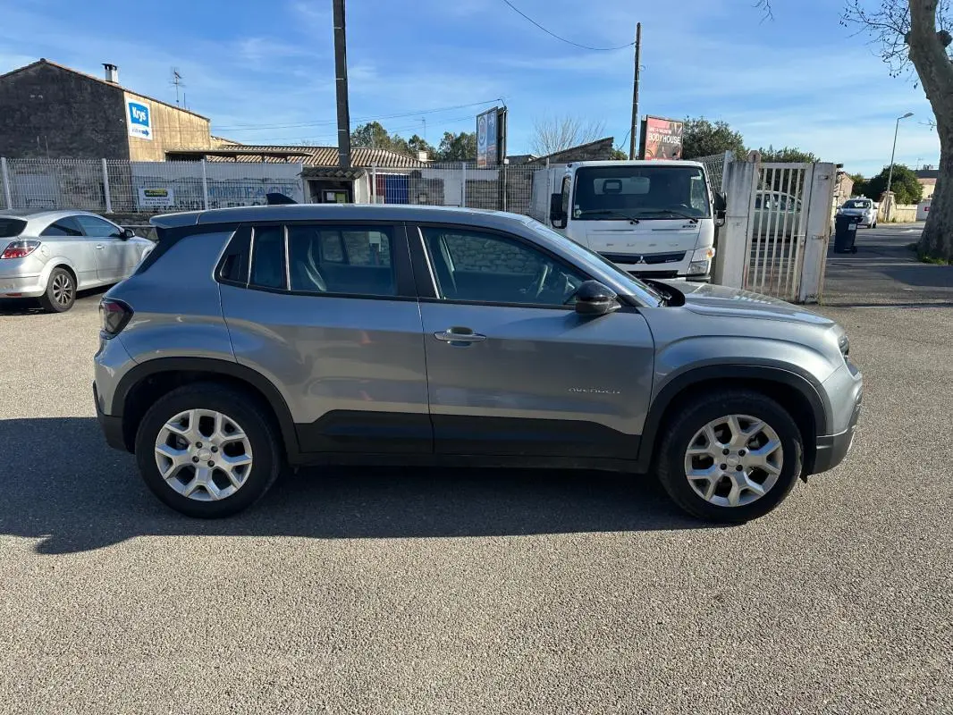 Vue de profil côté gauche d'un Jeep Avenger gris 2025 avec jantes alliage 17 pouces et protections noires sur les bas de caisse.