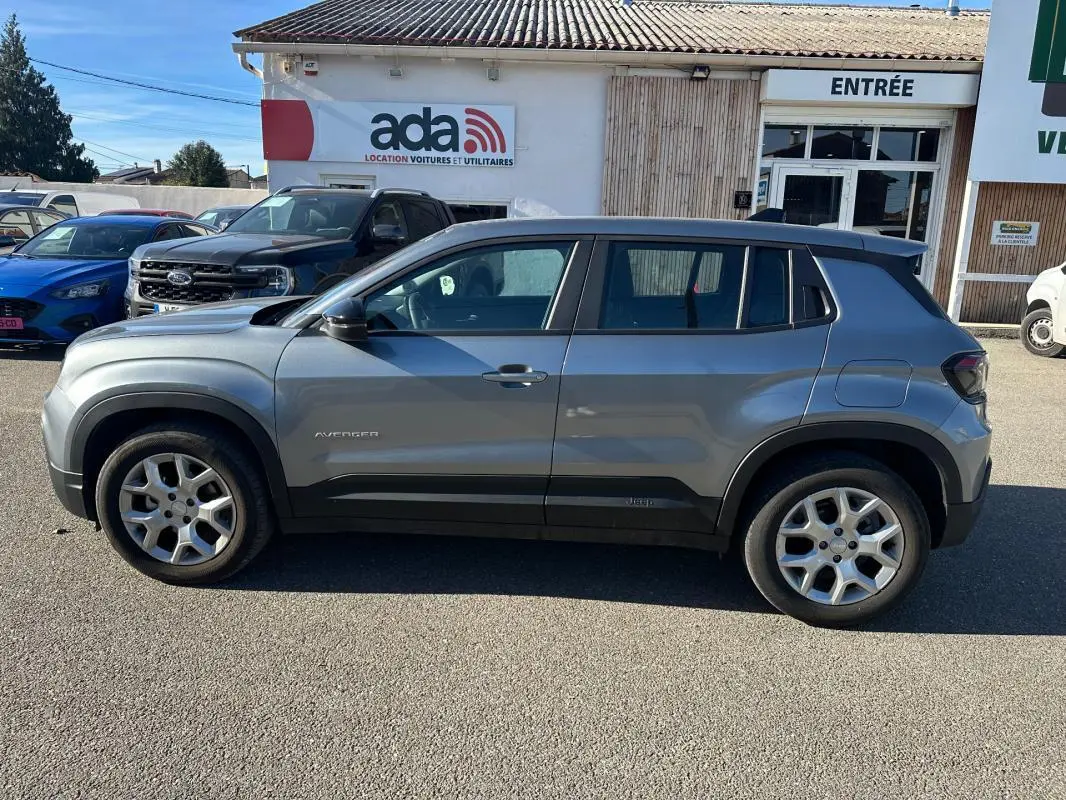Vue latérale droite du Jeep Avenger gris 2025 avec jantes alliage 17 pouces, sur parking devant un bâtiment.