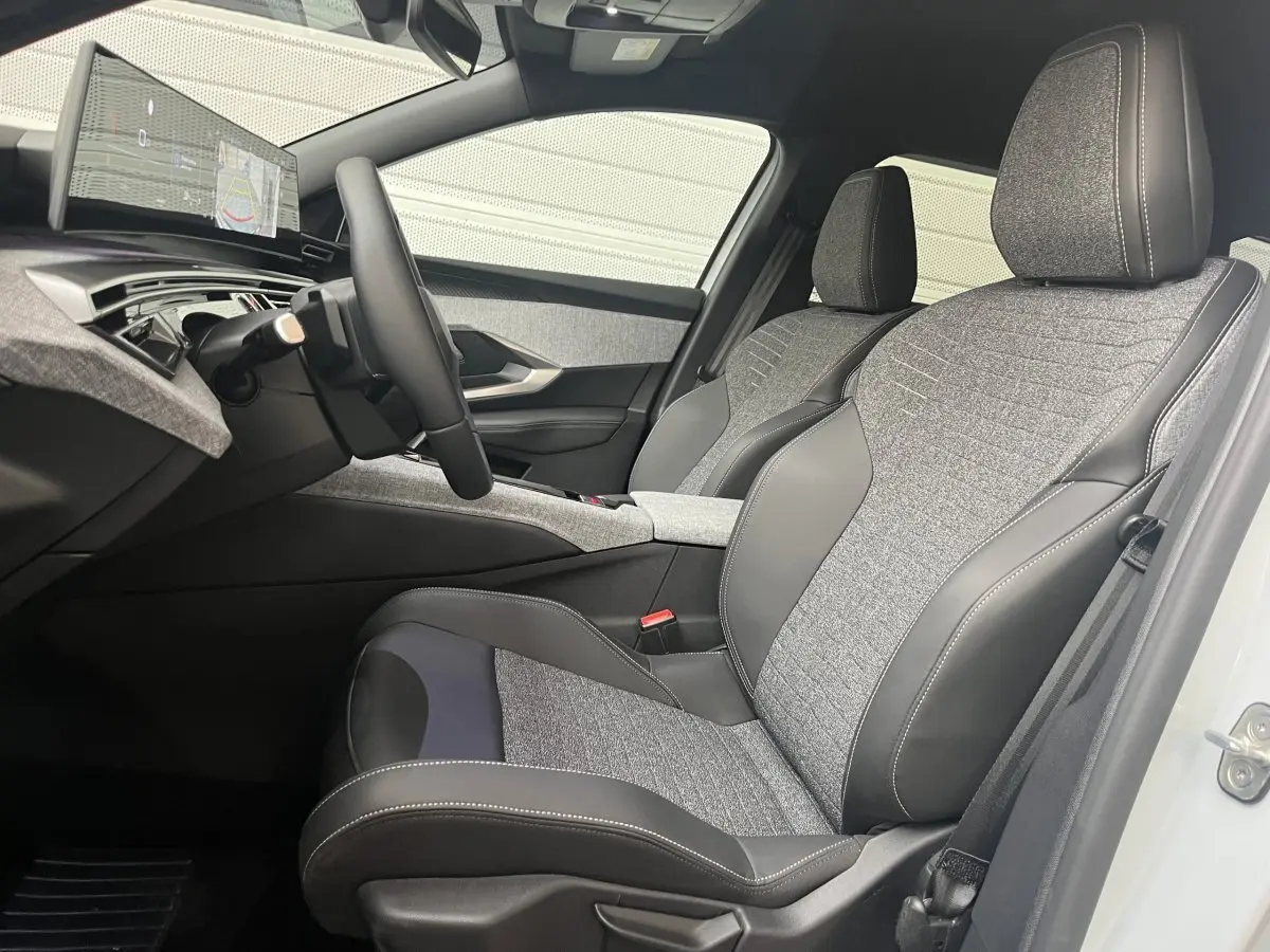 Vue intérieure côté conducteur du Peugeot 5008 Hybrid 145 Allure 2025 avec sièges tissu et cuir gris, volant multifonctions cuir.