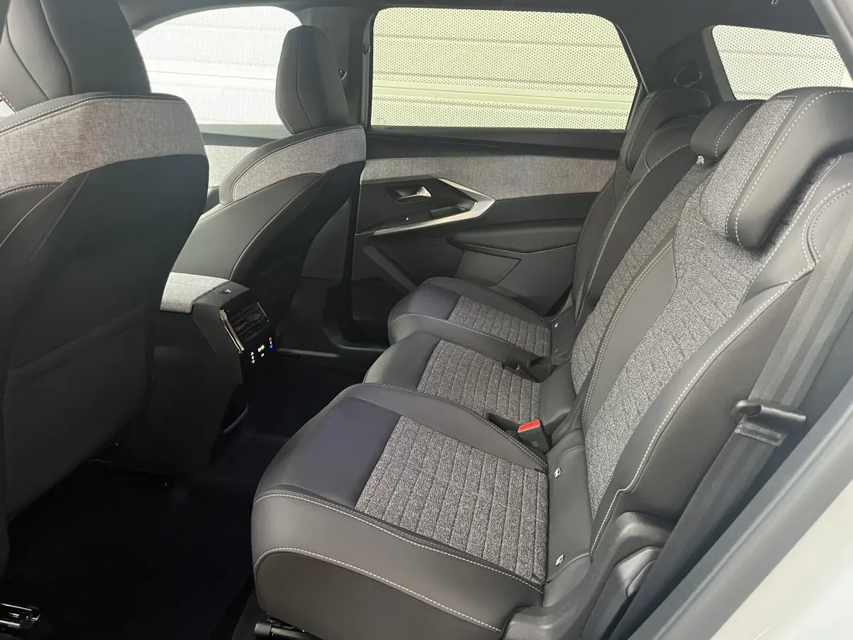 Vue intérieure côté droit sur la banquette arrière gris foncé et tissu clair du Peugeot 5008 Hybrid 2025 blanc.