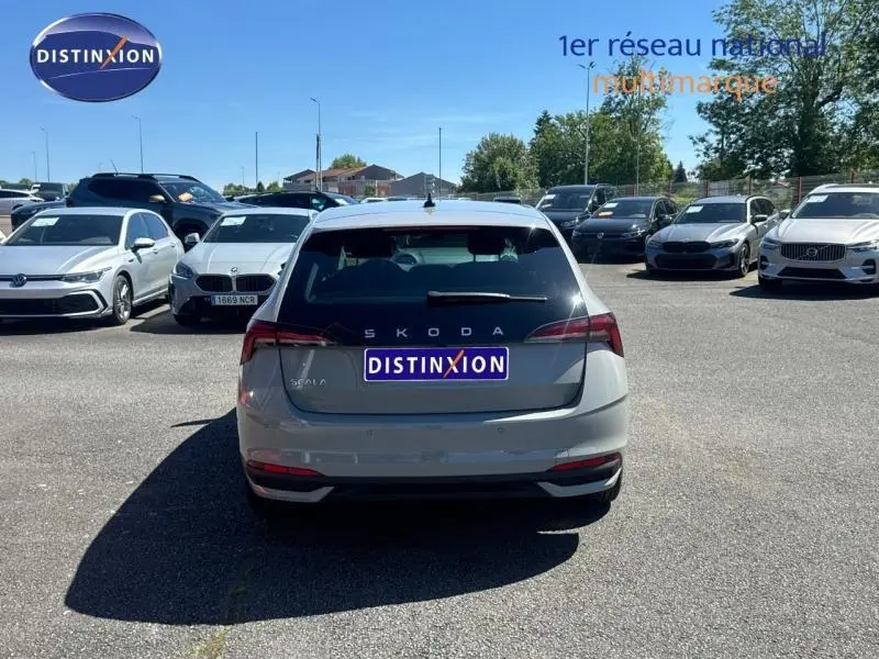 Vue arrière d'une Skoda Scala bleu clair garée en extérieur sur un parking sous un ciel dégagé.