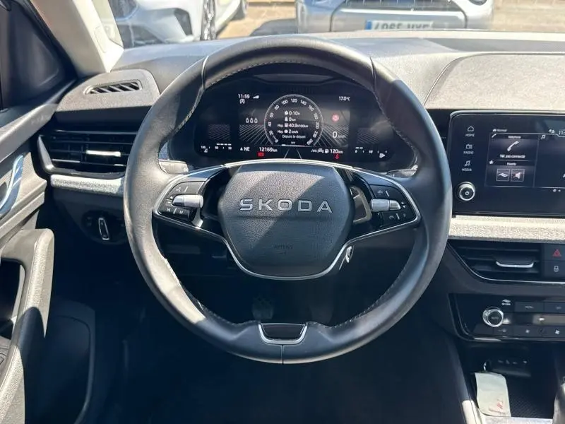 Vue centrée sur le volant cuir noir SKODA avec tableau de bord numérique et écran tactile à droite.