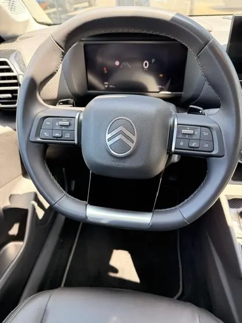Vue rapprochée du volant cuir noir multifonctions de la Citroën C4 Essence 130 EAT8 MAX avec tableau de bord numérique.