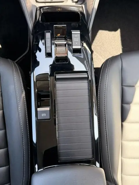 Vue plongeante sur la console centrale noire brillante de la Citroën C4 Essence 130 EAT8 MAX, avec commandes de boîte auto et frein électrique.