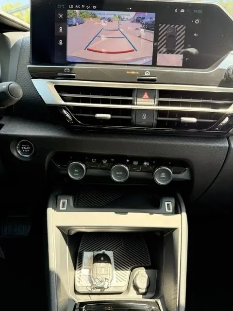 Vue intérieure du tableau de bord de la Citroën C4 2025, écran tactile affichant la caméra de recul et commandes climatisation.
