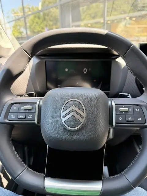 Vue rapprochée du volant cuir multifonctions noir de la Citroën C4 2025 avec logo central et commandes intégrées.