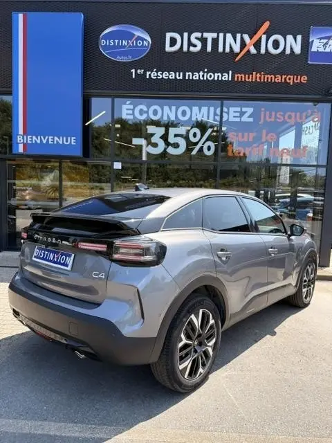 Vue 3/4 arrière droite d'une Citroën C4 gris foncé avec toit noir, feux arrière LED et jantes alliage distinctives.