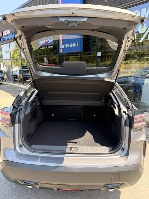 Coffre ouvert vu de l'arrière d'une Citroën C4 gris foncé, montrant un espace de chargement spacieux et propre.