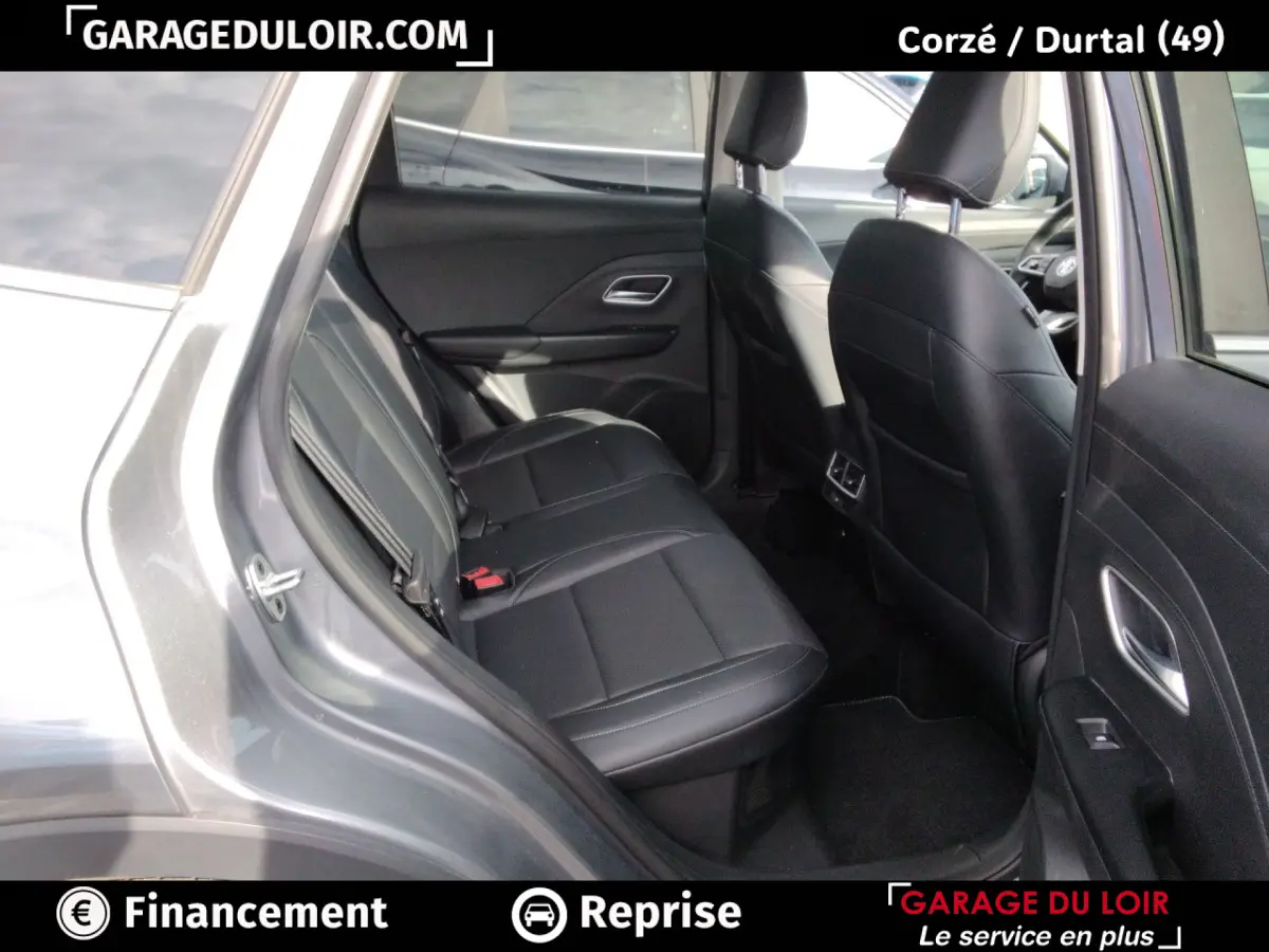 Vue intérieure arrière côté droit du MG Motor ZS gris clair 2025, sièges en cuir noir et accoudoir central visible.