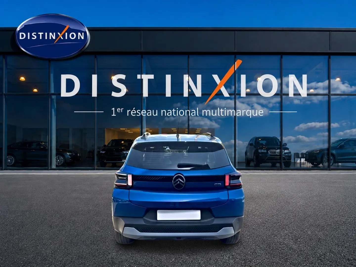 Vue arrière d'une Citroën C3 bleu 2025 stationnée devant une vitrine avec logo Distinxion.