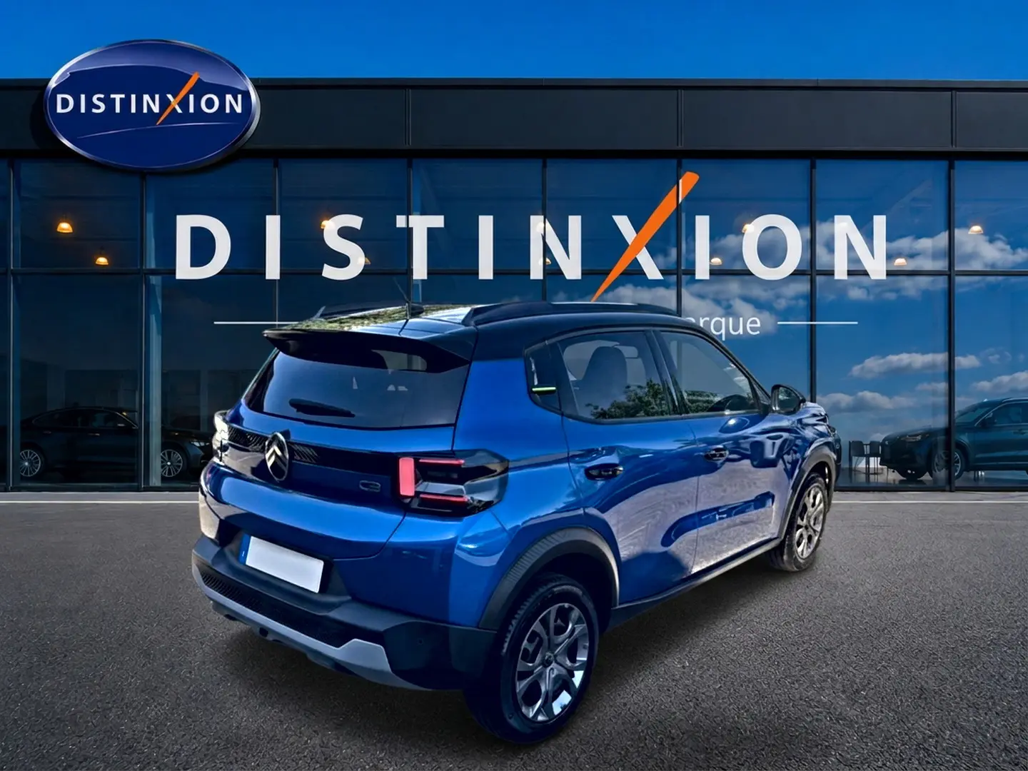 Vue 3/4 arrière droite d'une Citroën C3 bleue 2025 avec feux arrière LED et jantes alu devant un showroom Distinxion.